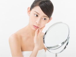 ニキビに悩み鏡を見ている女性