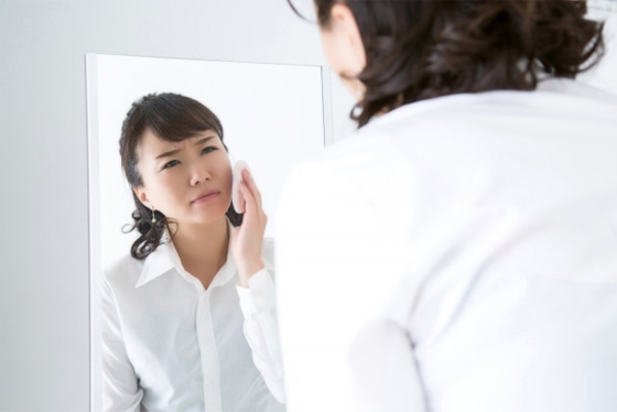 鏡の前でくすみを気にしている女性
